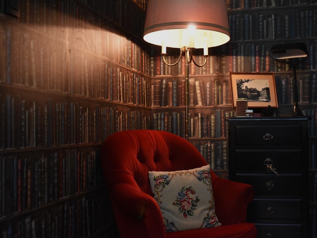 Coin lecture, fauteuil club et mur de livres anciens